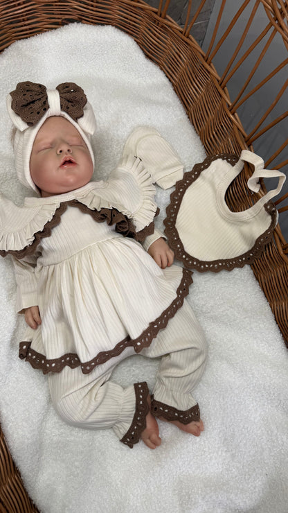 Zoom sur l’ensemble naissance fille, bavoir, gants, robe, pantalon et bandana